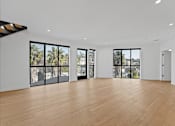 Thumbnail 76 of 119 - A spacious room with wooden floors and large windows overlooking a cityscape.