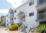 Thumbnail 8 of 32 - a white apartment building with stairs and a sidewalk