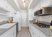 Thumbnail 1 of 18 - a kitchen with white cabinets and granite counter tops and a stove and microwave
