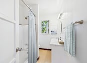 Thumbnail 10 of 24 - A white bathroom with a blue shower curtain.