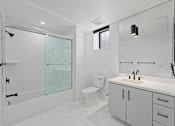 Thumbnail 85 of 119 - A white bathroom with a toilet, sink, and shower.