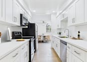 Thumbnail 1 of 19 - A modern kitchen with white cabinets and a black refrigerator.