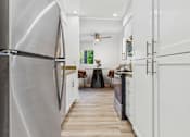 Thumbnail 1 of 29 - A modern kitchen with a stainless steel refrigerator and white cabinets.