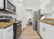 Thumbnail 2 of 29 - A kitchen with black and white appliances and wooden floors.