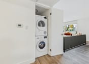 Thumbnail 9 of 29 - A white washing machine is in a small room.