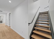 Thumbnail 78 of 119 - A long hallway with a staircase on the right side.