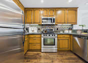 Thumbnail 2 of 88 - A kitchen with wooden cabinets and a stainless steel refrigerator.