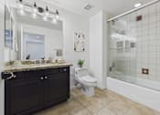Thumbnail 10 of 88 - A bathroom with a white toilet and a sink with a granite counter.
