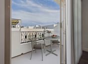 Thumbnail 6 of 88 - A balcony with a table and chairs overlooking a cityscape.