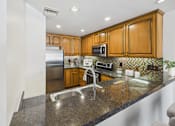 Thumbnail 3 of 88 - A kitchen with a granite counter top and wooden cabinets.