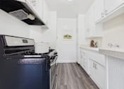 Thumbnail 11 of 30 - A kitchen with a black stove top oven and white cabinets.