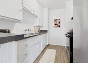 Thumbnail 2 of 30 - A kitchen with white cabinets and a black counter top.