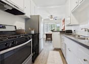 Thumbnail 1 of 30 - A modern kitchen with a black stove top oven and white cabinets.