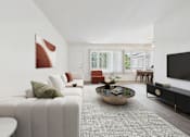 Thumbnail 7 of 30 - A modern living room with a white sofa, a coffee table, and a flat-screen TV.