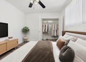 Thumbnail 9 of 30 - A bedroom with a large bed and a closet with clothes hanging.