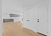 Thumbnail 86 of 119 - A white room with a wooden floor and two white doors.