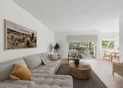Thumbnail 3 of 15 - A living room with a grey couch and a painting on the wall.