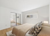 Thumbnail 8 of 15 - A bedroom with a bed and a mirror on the wall.