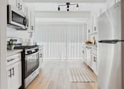 Thumbnail 3 of 12 - A modern kitchen with white cabinets and stainless steel appliances.