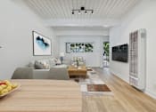 Thumbnail 5 of 12 - A modern living room with a grey couch, a wooden table, and a painting on the wall.