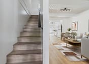 Thumbnail 6 of 12 - A staircase with a wooden tread and riser leads to a living room.