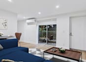 Thumbnail 7 of 39 - A blue couch sits in a living room with a coffee table in front of it.