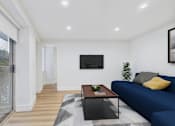 Thumbnail 8 of 39 - A modern living room with a blue couch and a flat screen TV mounted on the wall.