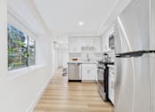 Thumbnail 2 of 39 - A modern kitchen with white appliances and wooden floors.