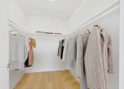 Thumbnail 28 of 39 - A row of clothes hanging on a rack in a white room.