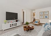 Thumbnail 5 of 21 - A living room with a white couch, a wooden coffee table, and a flat screen TV.