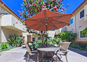 Thumbnail 71 of 78 - A patio with a table, chairs and an umbrella.