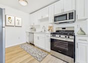 Thumbnail 1 of 78 - A kitchen with white cabinets and a stainless steel oven.