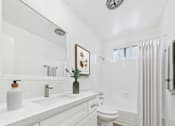 Thumbnail 11 of 78 - A white bathroom with a toilet, sink, and shower.