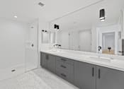 Thumbnail 80 of 119 - A bathroom with a white sink and grey cabinets.