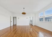 Thumbnail 10 of 23 - A large empty room with wooden floors and white walls.