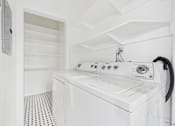 Thumbnail 17 of 23 - A white washing machine in a laundry room.