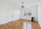 Thumbnail 9 of 23 - A room with a wooden floor and a chandelier.