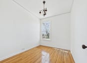 Thumbnail 15 of 23 - A room with a wooden floor and a chandelier.
