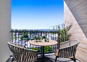 Thumbnail 4 of 90 - A balcony with a table and two chairs overlooking a street.