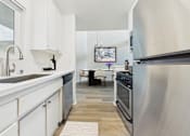Thumbnail 3 of 108 - A modern kitchen with white cabinets and a wooden floor.