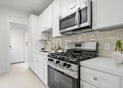 Thumbnail 3 of 32 - A modern kitchen with white cabinets and a black stove top.