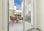 Thumbnail 7 of 61 - A patio with a table and chairs is visible through a glass door.