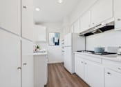 Thumbnail 1 of 23 - A kitchen with white cabinets and a wooden floor.
