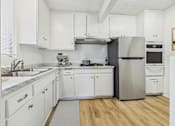 Thumbnail 1 of 36 - A kitchen with white cabinets and a stainless steel refrigerator.