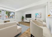 Thumbnail 5 of 36 - A living room with a white couch, a white chair, a white coffee table, a white fireplace, a white TV, and a white wall.
