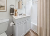 Thumbnail 10 of 36 - A bathroom with a white tub, sink, and toilet paper holder.
