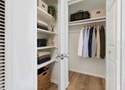 Thumbnail 9 of 36 - A white closet with clothes hanging and towels folded on shelves.