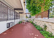Thumbnail 32 of 36 - A patio with a red floor and a white wall with a black gate.