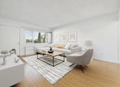 Thumbnail 5 of 13 - A living room with a white couch, a coffee table, and a chair.