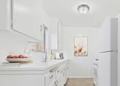 Thumbnail 1 of 13 - A white kitchen with a bowl of fruit on the counter.